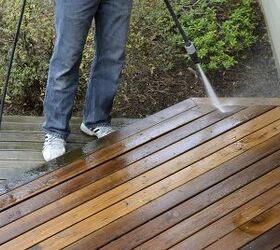 this is how to pressure wash a deck the right way, person in jeans power washing the edge of a wood deck