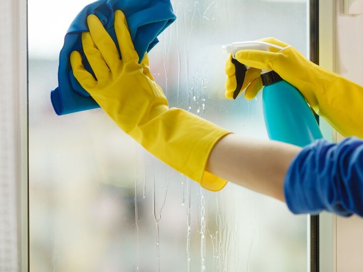 Yellow gloved hands wiping down glass window / Photo via Shutterstock