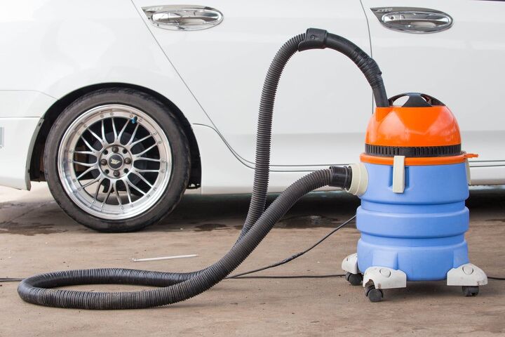 the 6 best shop vacs to clean up messy projects, Blue and orange shop vac next to a white car Photo via Shutterstock