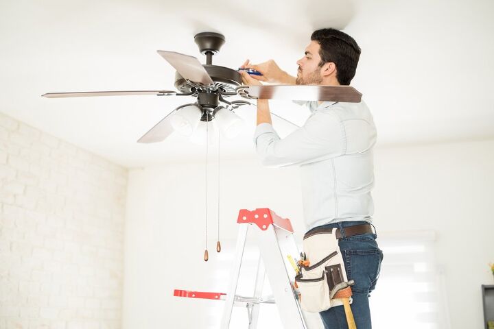 how to fix a wobbly ceiling fan, man on ladder tightening ceiling fan motor housing