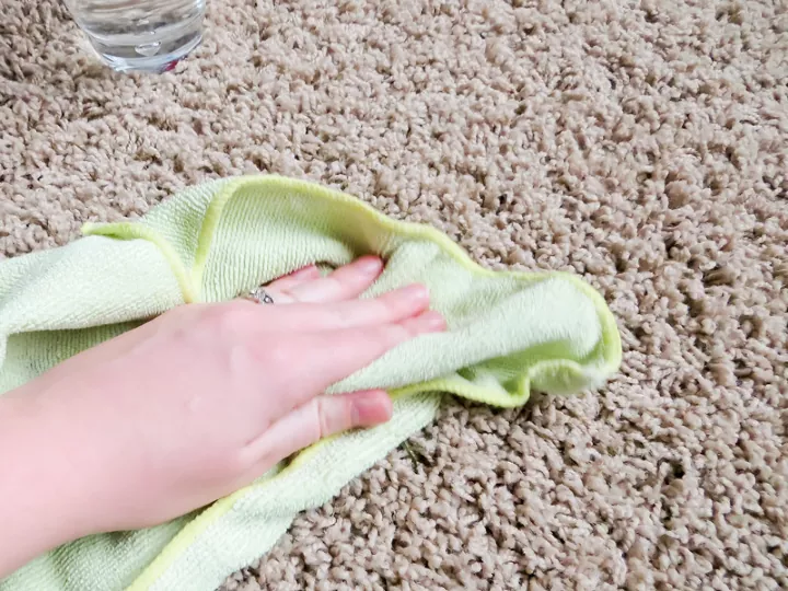 Hand rubbing green microfiber towel on carpet / Photo via Angela