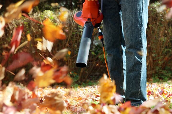person holding leaf blower to blow leaves / Photo via Shutterstock