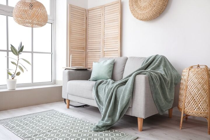 green blanket draped over gray couch / Photo via Shutterstock