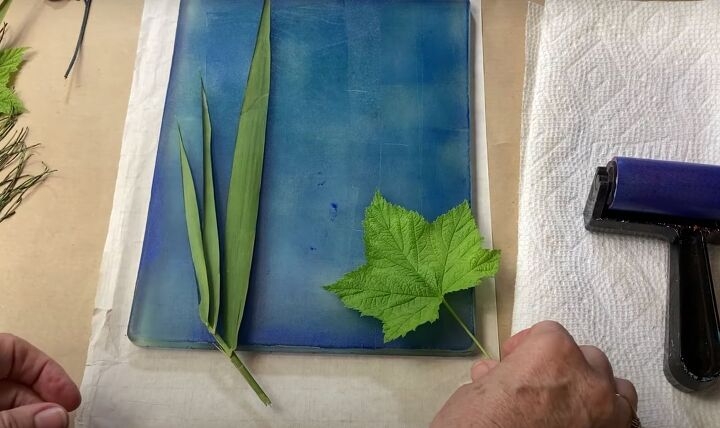 the surprisingly easy way to make your own botanical prints, Arranging greenery on a gel press printing plate painted blue