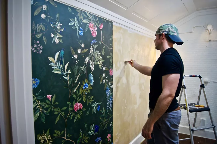 how to hang wallpaper, man putting up floral print wallpaper