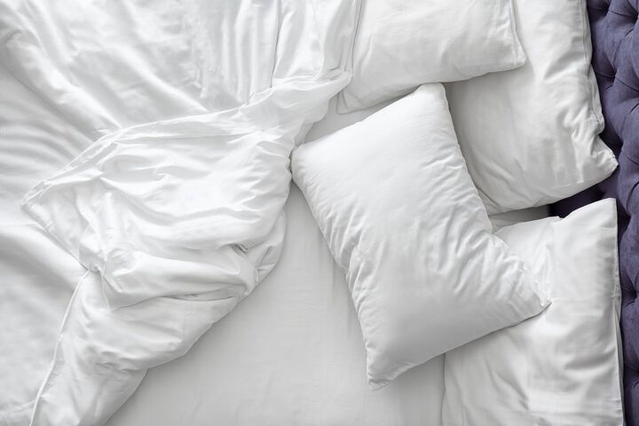 Unmade bed with white sheets, pillows, and comforter / Photo via Shutterstock