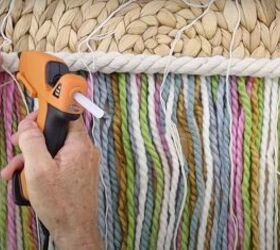 here s how to make gorgeous boho rainbow wall decor, Attaching tassels to the top of the tapestry with hot glue