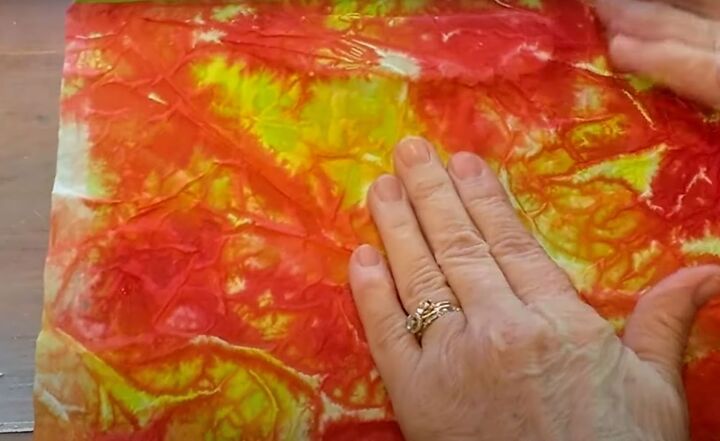 brighten storage bins with vibrant tie dyed tissue paper, Smoothing the paper onto the box with hands