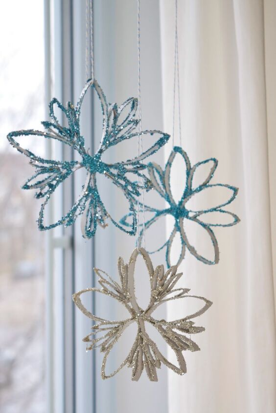 how to make festive glitter toilet paper roll snowflakes, Three glittery snowflakes hanging from a curtain rod