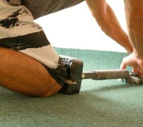 a complete guide on how to stretch carpet yourself, person using knee kicker to push carpet