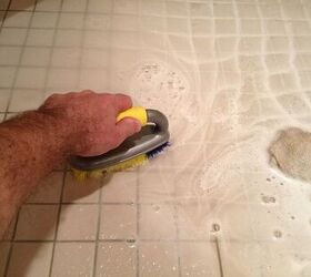 how to get rid of pink mold, hand using scrub brush against tiles
