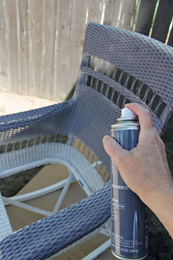 how to paint wicker furniture to give it a new look, hand spraying black paint onto wicker chair