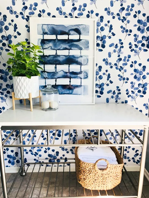 how to apply peel and stick wallpaper, white and blue floral peel and stick wallpaper behind table with decorations and plant