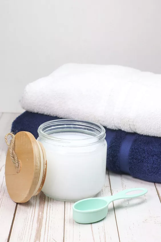 best laundry detergents for odors, glass jar of white laundry detergent next to towels photo via Reesa