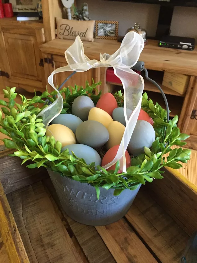 how to get easter egg dye off skin without harsh chemicals, basket of dyed easter eggs and greenery