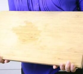 how to clean a wood cutting board disinfect it and lift pesky stains, person holding wood cutting board with stain