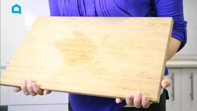 how to clean a wood cutting board disinfect it and lift pesky stains, person holding wood cutting board with stain