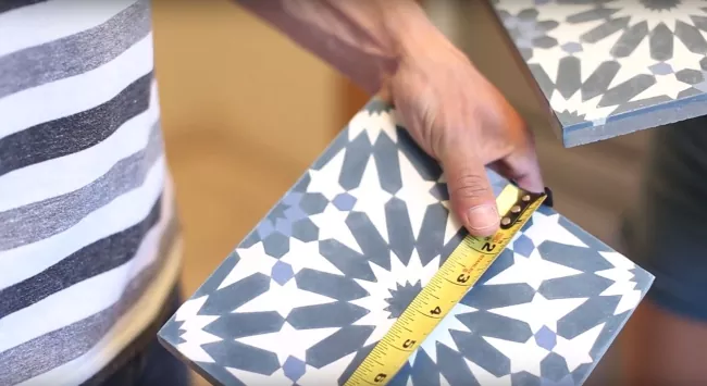 how to tile over tile the right way, person measuring width of patterned tile