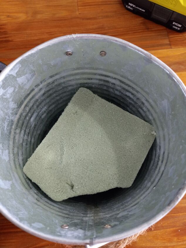 how to make a cute farmhouse pulley hanging bucket planter, Adding floral foam to the pail