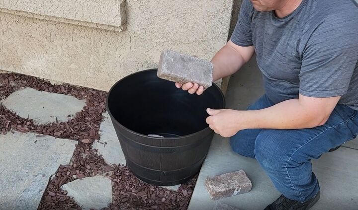 mesmerize your guests with this fancy floating fountain diy, Stabilizing the plastic planter by placing bricks at the bottom