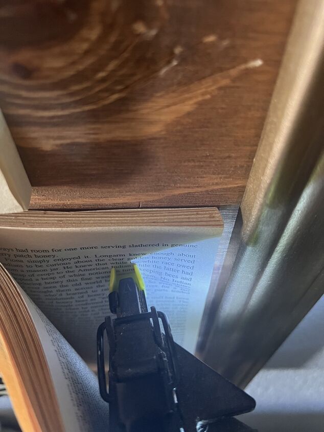 arte de pared de libros para inquilinos diy, Puedes ver aqu que tengo un buen trozo de p ginas de libro debajo de mi pistola de clavos esto ayuda a asegurar que no perfores la parte posterior de tu madera contrachapada o atravieses la pared