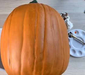 tallar una calabaza de espuma con un patrn de tallado, calabaza junto a pinturas y toalla de papel con vetas de aint en la calabaza