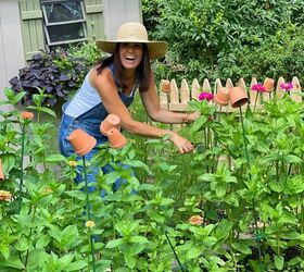 cmo hacer una bola de besos de navidad, Stacy Ling bloguera de Hogar y Jard n cortando flores de zinnia en su jard n de casa de campo con valla de madera delante de la caseta de jard n