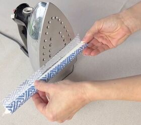 3 quick and easy decorative taper candle projects, Rolling a taper candle wrapped in a patterned napkin onto a heated iron