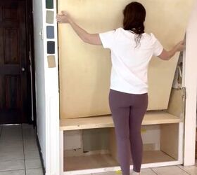 diy mudroom armarios, una mujer instala el panel trasero de un armario empotrado en un guardarropa de bricolaje