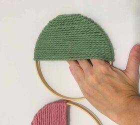 anillo de lana moderno para colgar en la pared, mano presionando contra la pared el interior del aro de lana donde est pegado el adhesivo