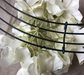 cmo hacer una corona de primavera con hortensias, Una flor de hortensia blanca bajo la forma de corona con un trozo de alambre floral insertado a trav s de la forma y la flor Paso cuatro para ver c mo hacer una corona de primavera con hortensias