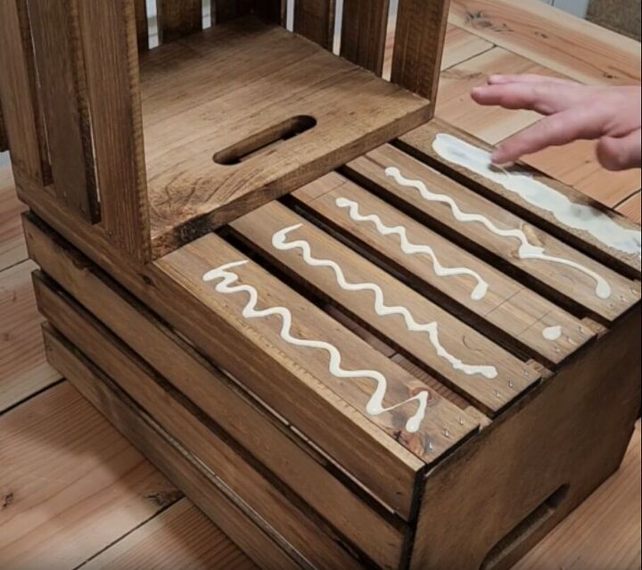 how to make an impressive rustic diy wood crate coffee table, Applying wood glue to a wooden crate