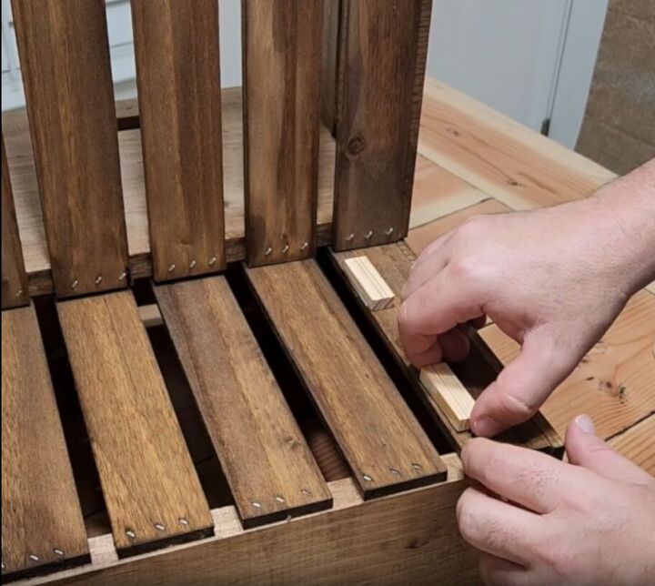 how to make an impressive rustic diy wood crate coffee table, Sticking small Jenga pieces onto the top strip of a wooden crate