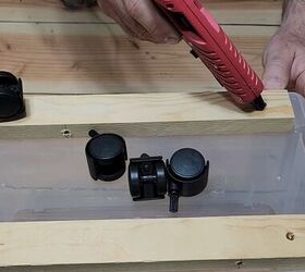 3 easy steps to a stylish diy plastic storage bin makeover, Adding hot glue to the predrilled holes for the caster wheels