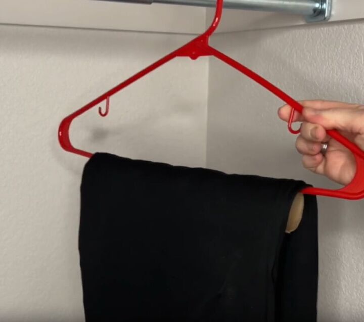 12 amazing hanger hacks to keep your home organized, A hanger with a cardboard toilet paper tube attached and a pair of pants hanging over to prevent creases
