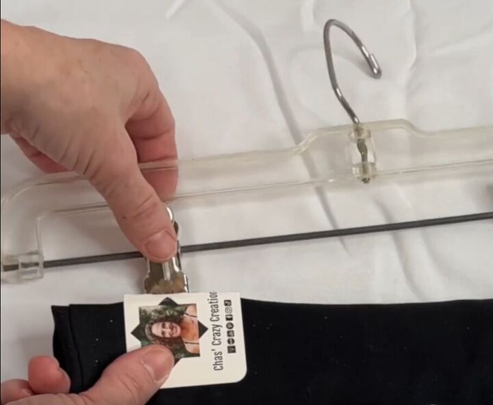 12 amazing hanger hacks to keep your home organized, A folded busines card placed over the top of a pair of pants before attaching it to the clip of a pants hanger