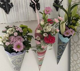 sorprende a tus vecinos con una cesta del primero de mayo, Tres cestas de papel llenas de flores colgadas de un perchero