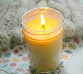 ideas para hacer velas con aroma de ylang ylang, una vela Mason jar encendida cerca de una manta