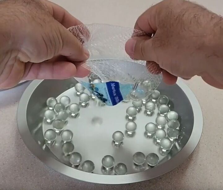 Pouring marbles into the larger cake pan for DIY Lazy Susan