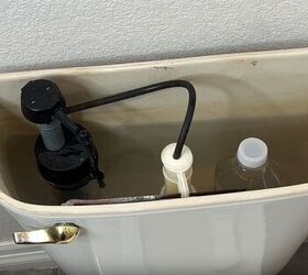 toilet cleaning hacks, A vinegar bottle strategically positioned inside a toilet tank
