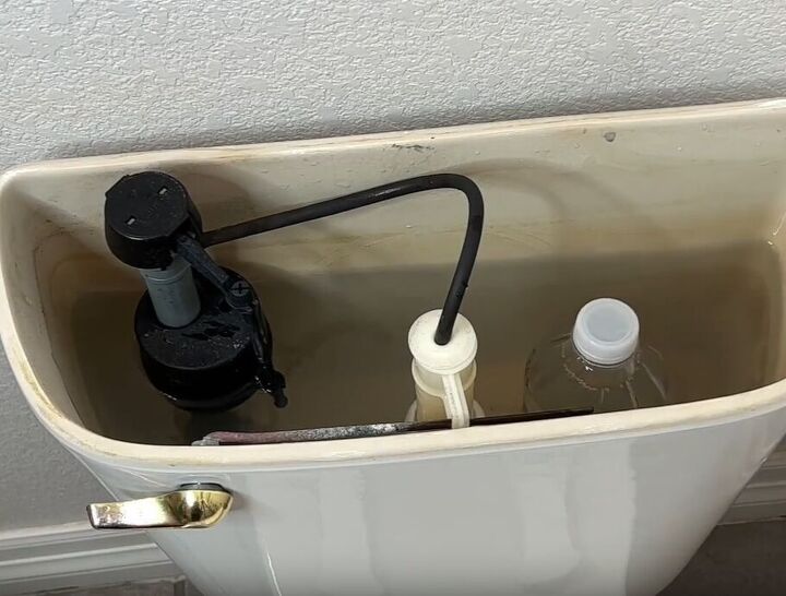 toilet cleaning hacks, A vinegar bottle strategically positioned inside a toilet tank