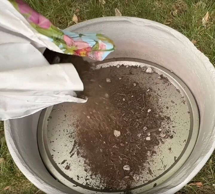 Adding soil to the top of the pizza pan in the flower pot
