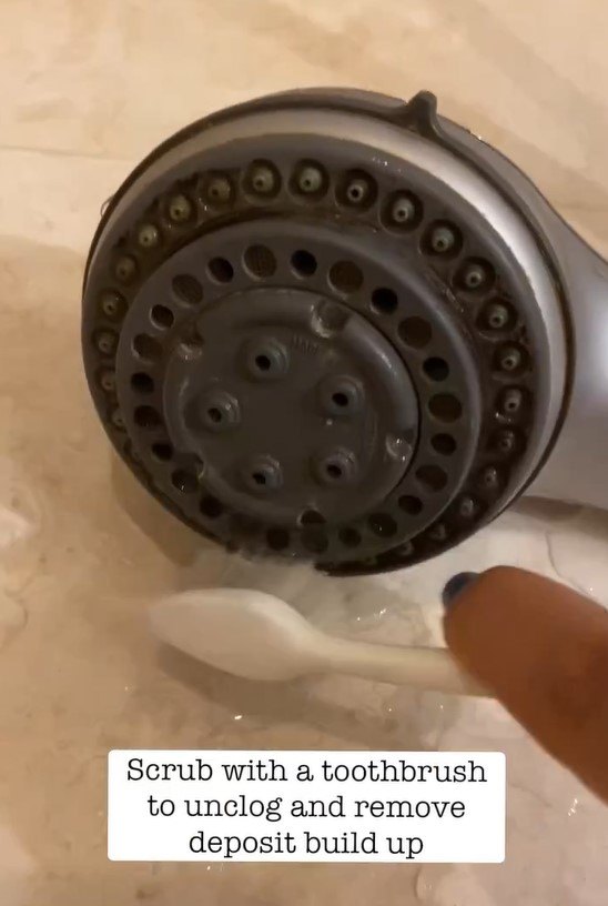Cleaning the showerhead with an old toothbrush