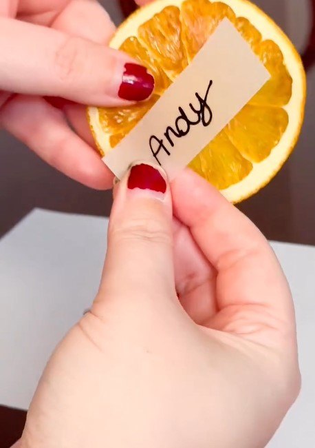 Attaching the place cards to the citrus slices