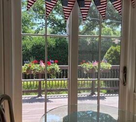 quieres una idea realmente fcil para decorar la mesa el 4 de julio, Esta es una foto de mi mesa de cristal para dos con vistas a mi terraza que tiene jardineras llenas de geranios rojos y flores azules Encima de las puertas francesas hay un bander n patri tico con la bandera americana