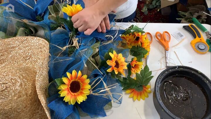 Gluing faux sunflowers to the wreath