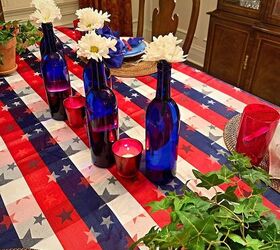 cmo hacer un divertido rojo blanco azul tablescape, Botellas de cristal azules con margaritas blancas y votivas rojas para un festivo centro de mesa rojo blanco y azul