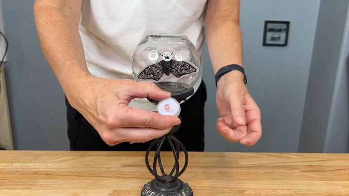 Insert an LED candle under the upside down bud vase