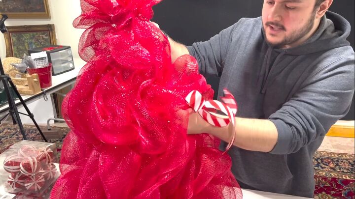 Poking the pipe cleaners into the deco mesh tomato cage Christmas tree