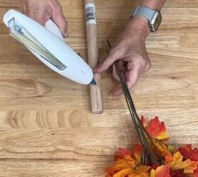 Applying hot glue to the plunger for the fall tree craft